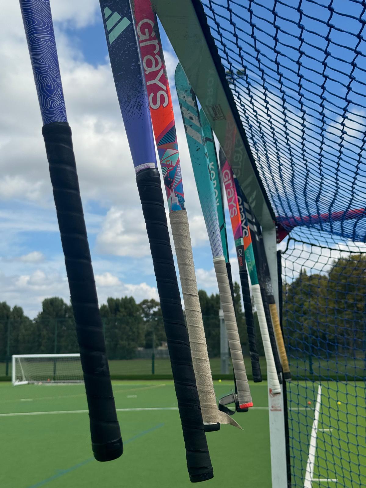 Row of hockey sticks hanging on the goal against a blue sky