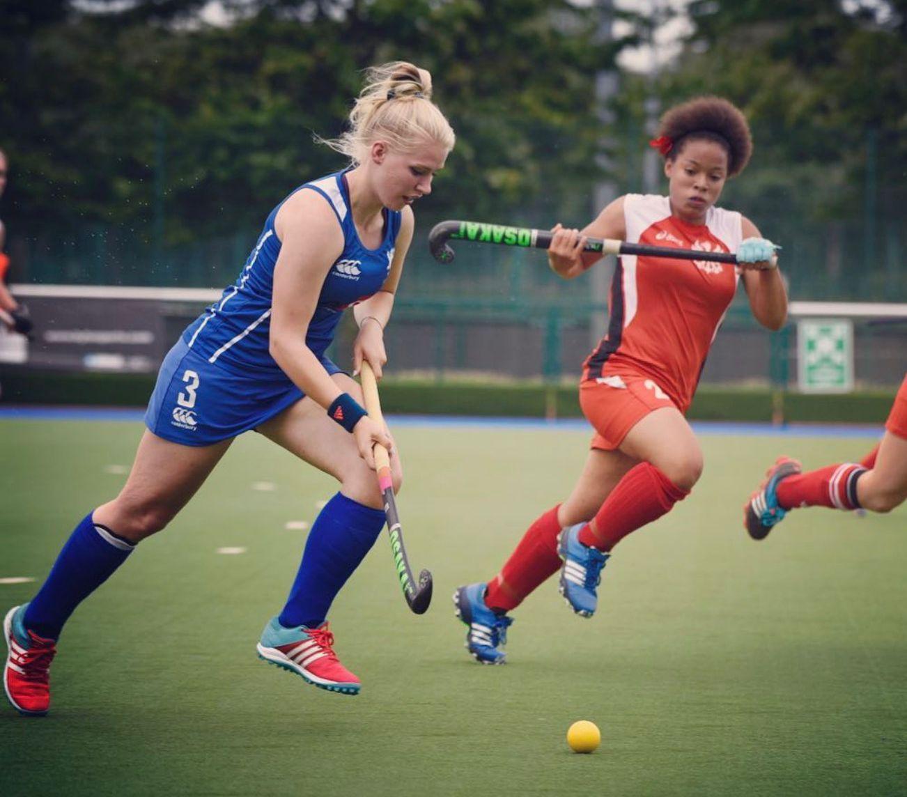 Bella Fisken driving past a defender during a hockey match