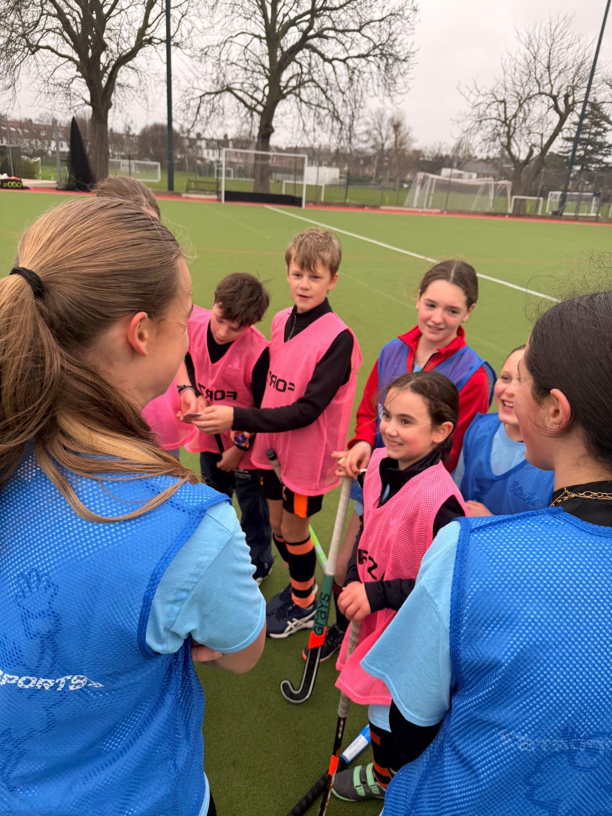 Young campers in coloured bibs gathered for a coaching huddle